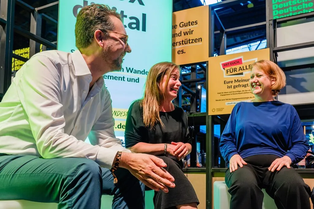 Three people sit together laughing.