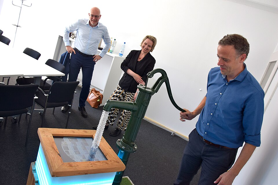 Markus Richter operates a pump. Instead of water, there is a screen displaying data.