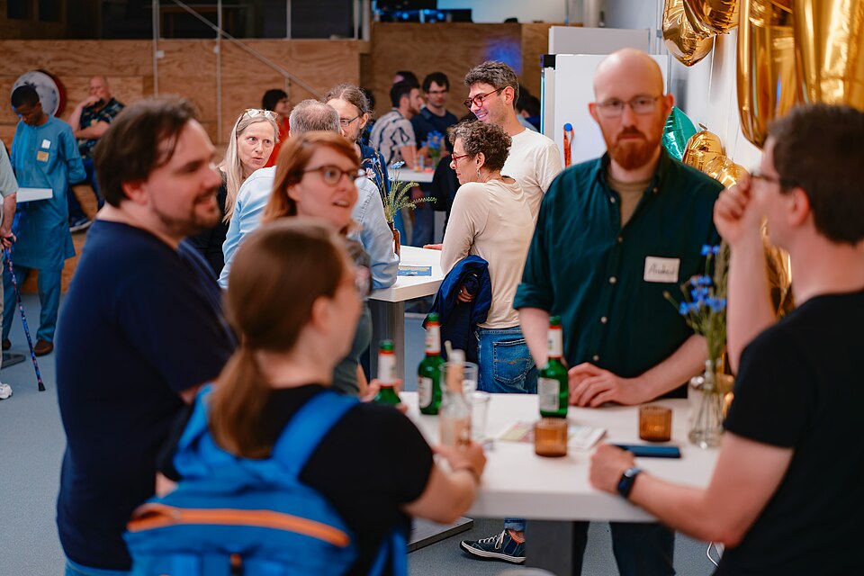 Menschen stehen an Tischen und unterhalten sich