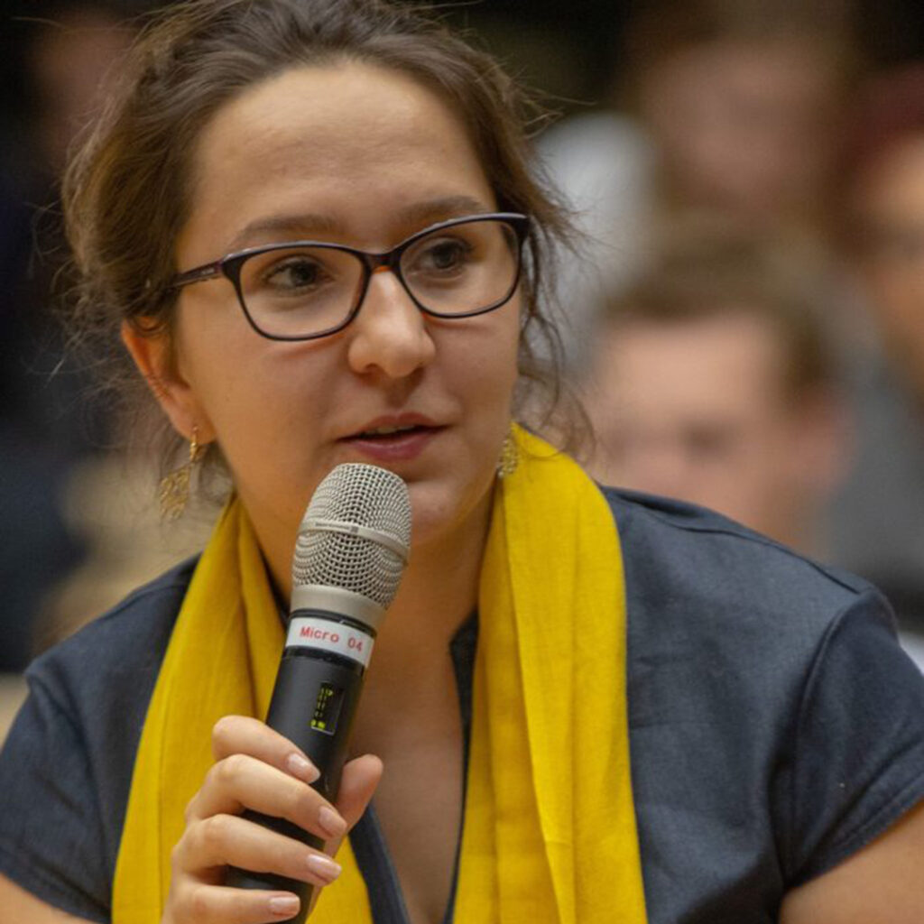 Hajdi Barz, founding member of RomaniPhen e.V., holding a microphone.