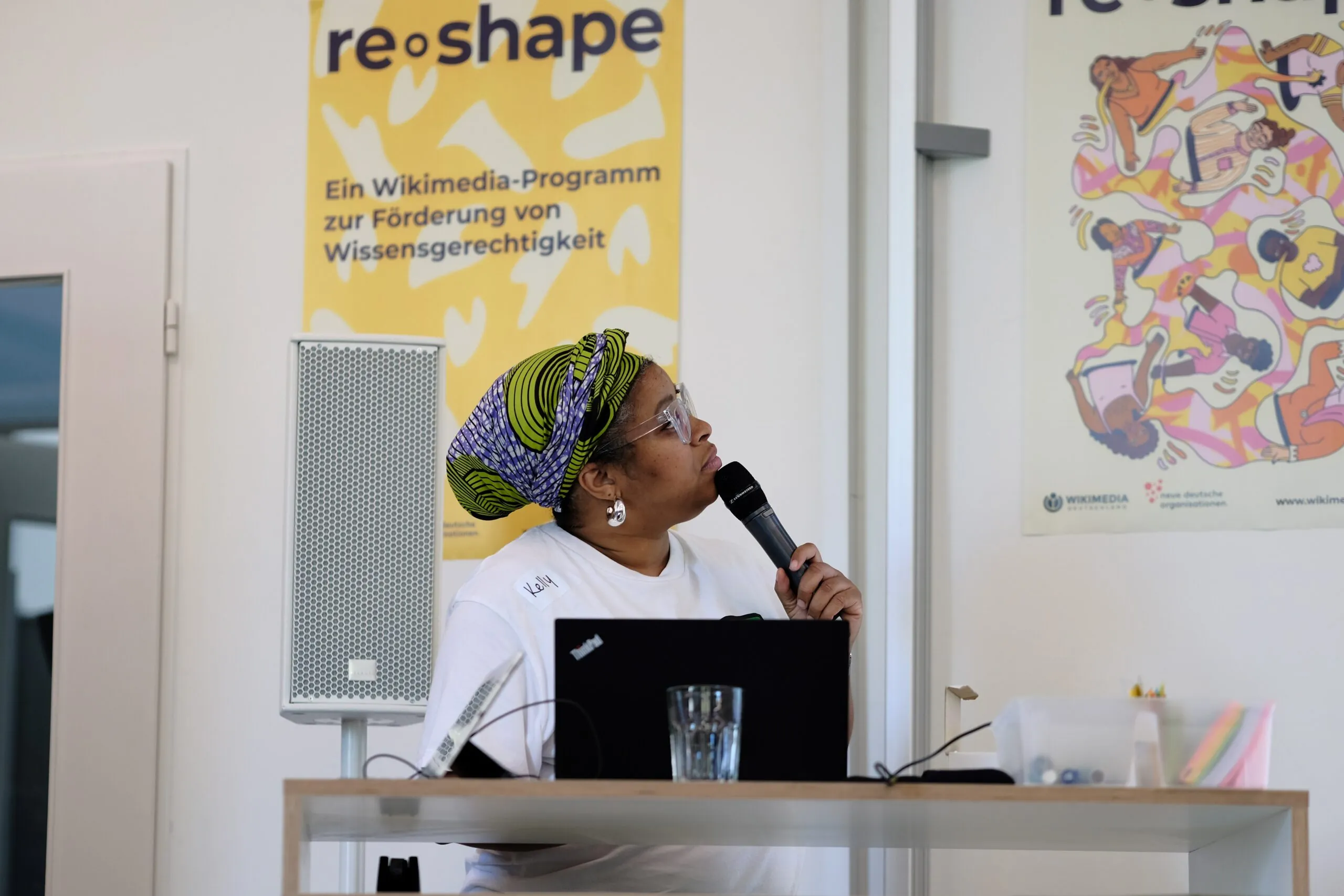 A person is looking to the right and holding a microphone in their hand.