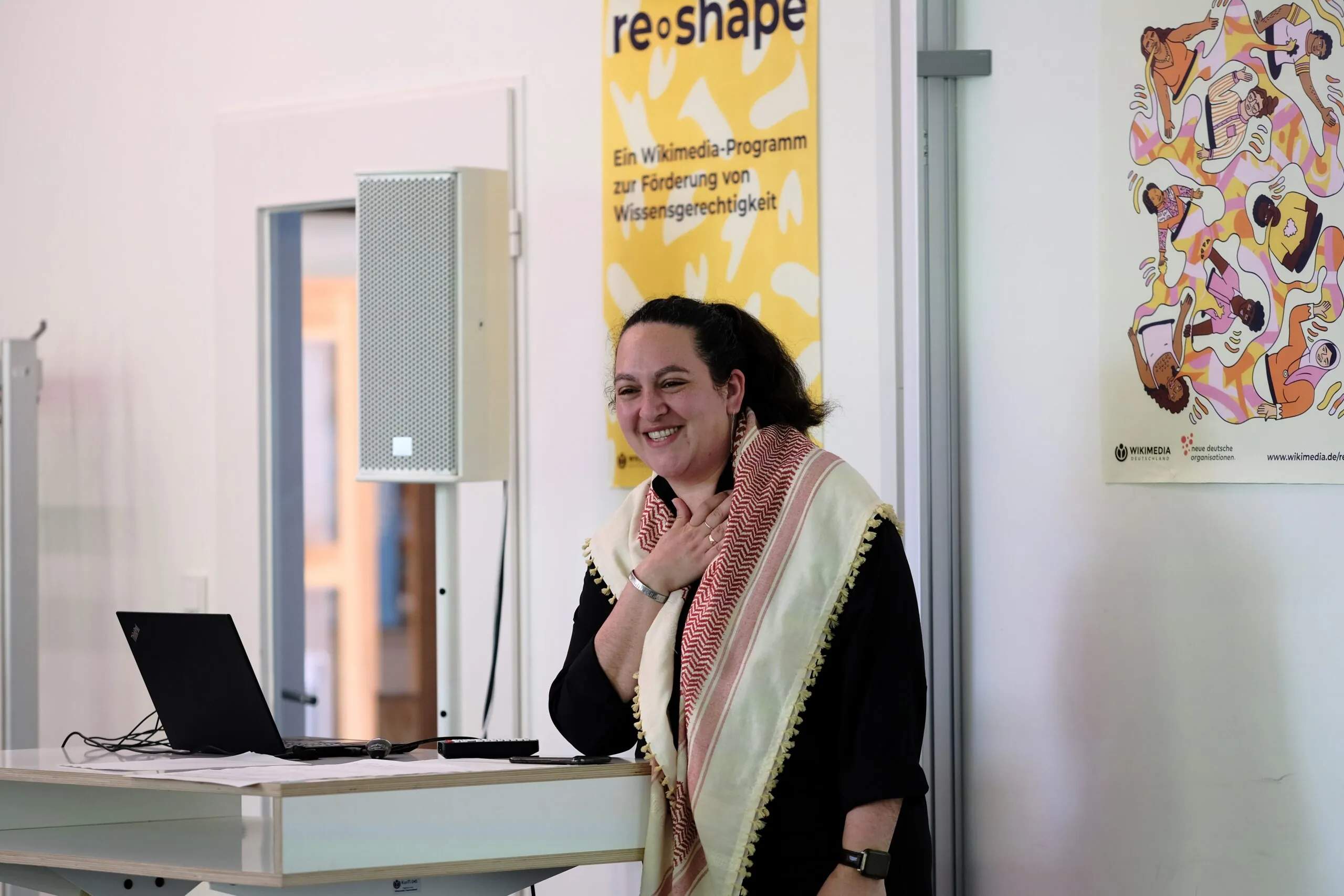 A person stands at a desk and smiles.