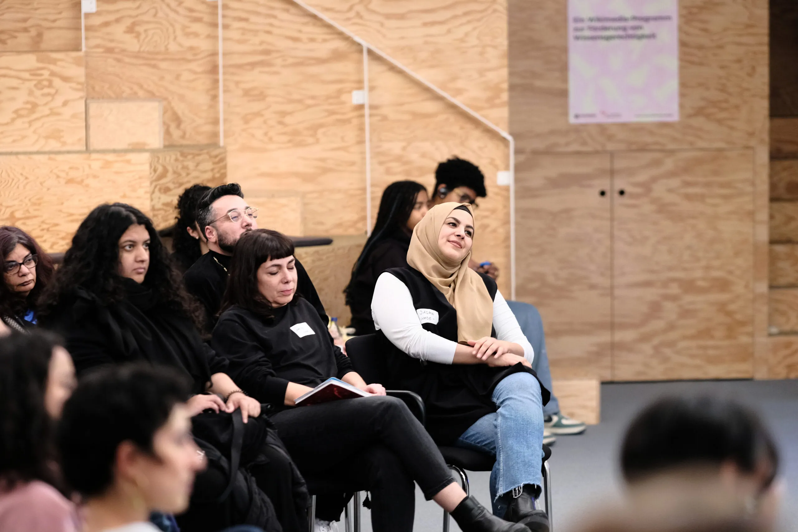 Participants in the workshop sit together and look at a point next to the camera.