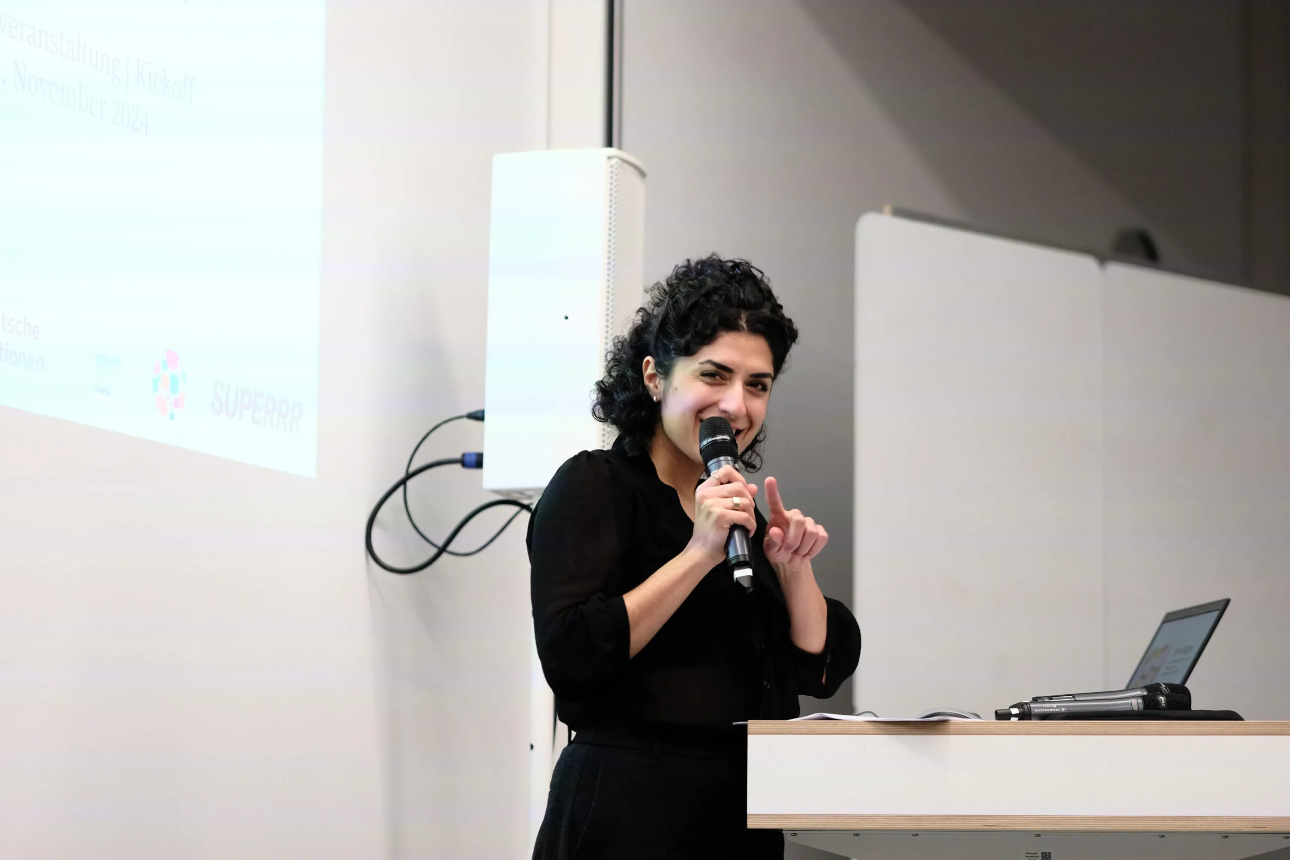 A person is standing at a desk with a microphone in their hand.