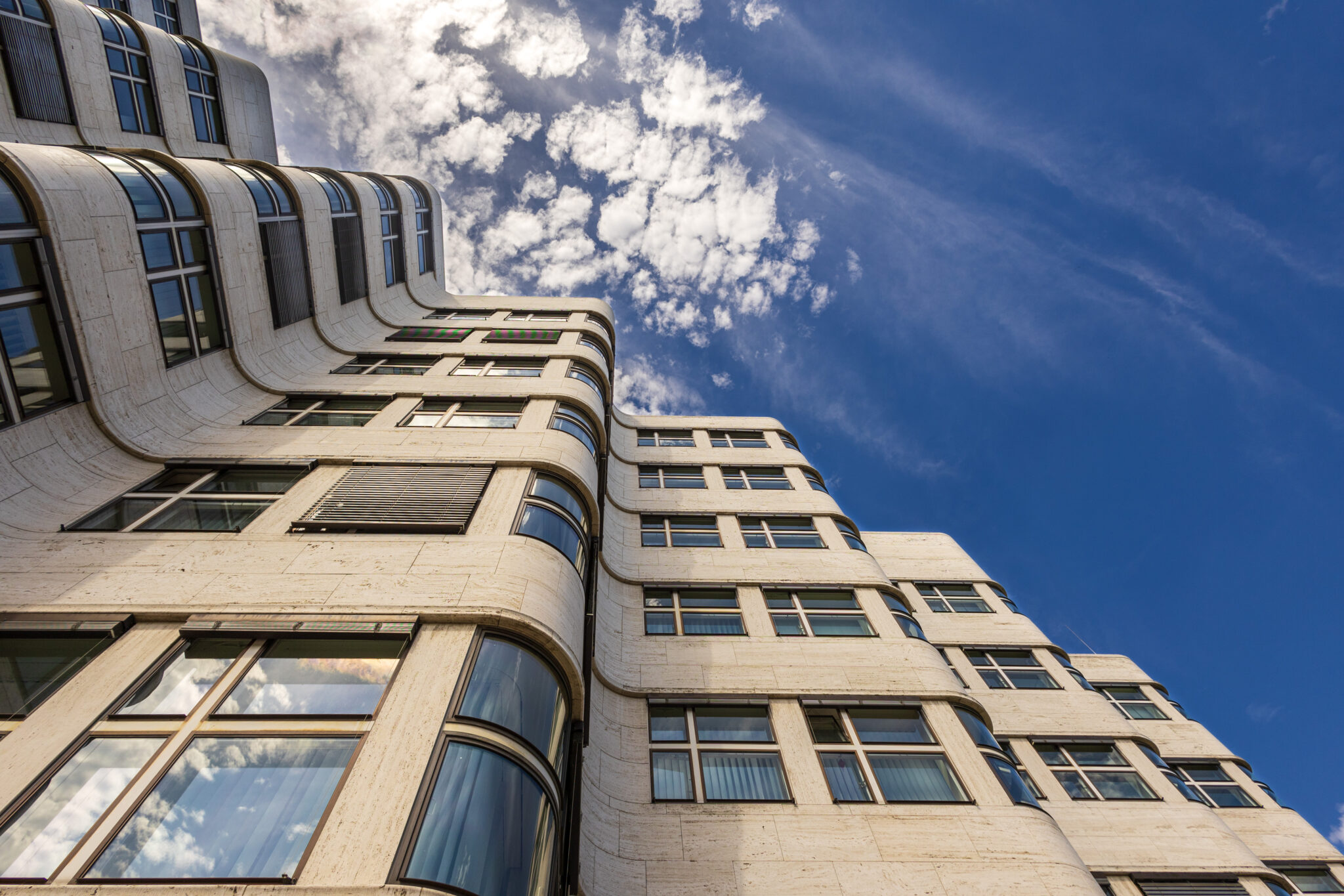 Shell-Haus Berlin aus Froschperspektive mit blauem Himmel und Wolken.