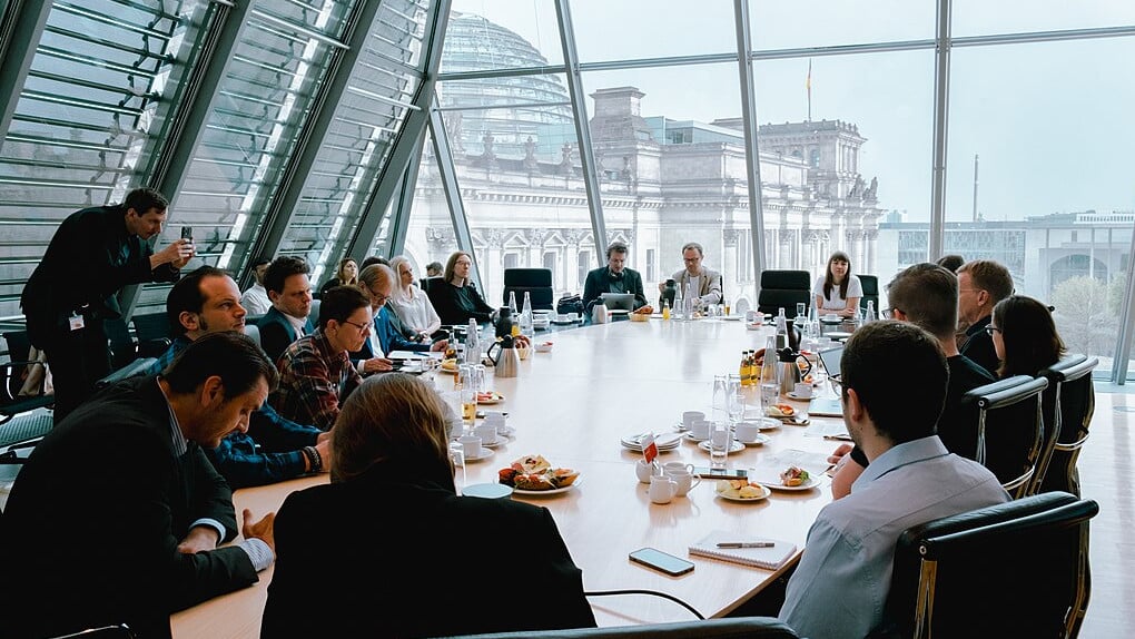 Menschen, in einem großen Konferenzraum, an einem Großen Tisch, essen Frühstück.