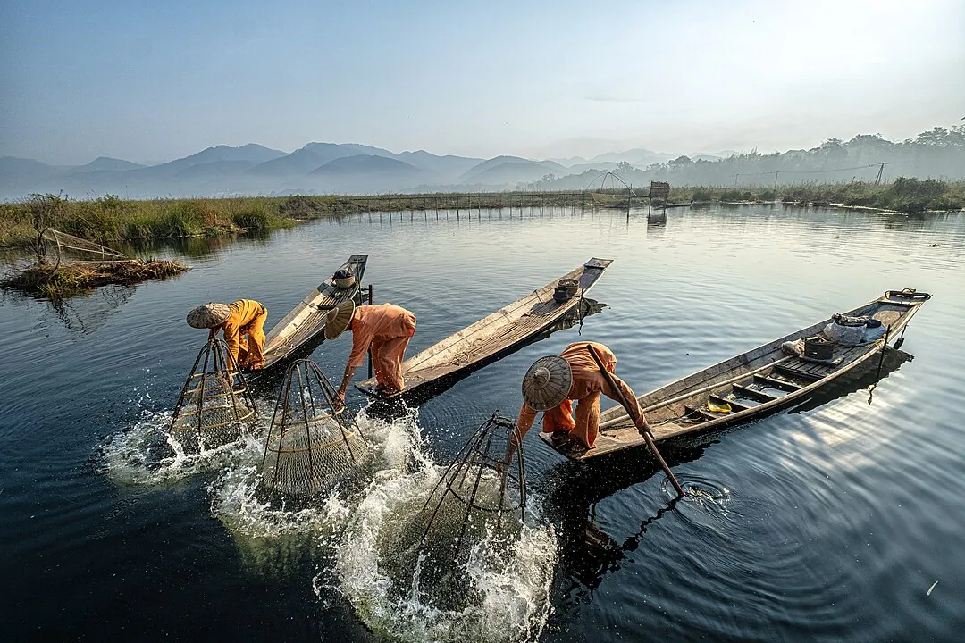 Sonnenaufgang über dem Inle-See mit traditionellen Fischerbooten.
